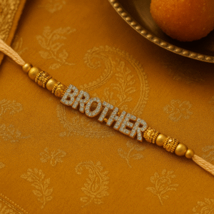 A close-up of a "Brother Rakhi" on a wrist, featuring "BROTHER" spelled out in sparkling, studded gold-toned letters, flanked by decorative golden beads on a subtle, light-colored thread, symbolizing deep sibling affection.