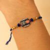 A trendy "Bro Rakhi" featuring a minimalist design, perhaps a metallic charm saying "BRO" or a cool geometric pattern, displayed casually on a wrist, representing a modern sibling bond.