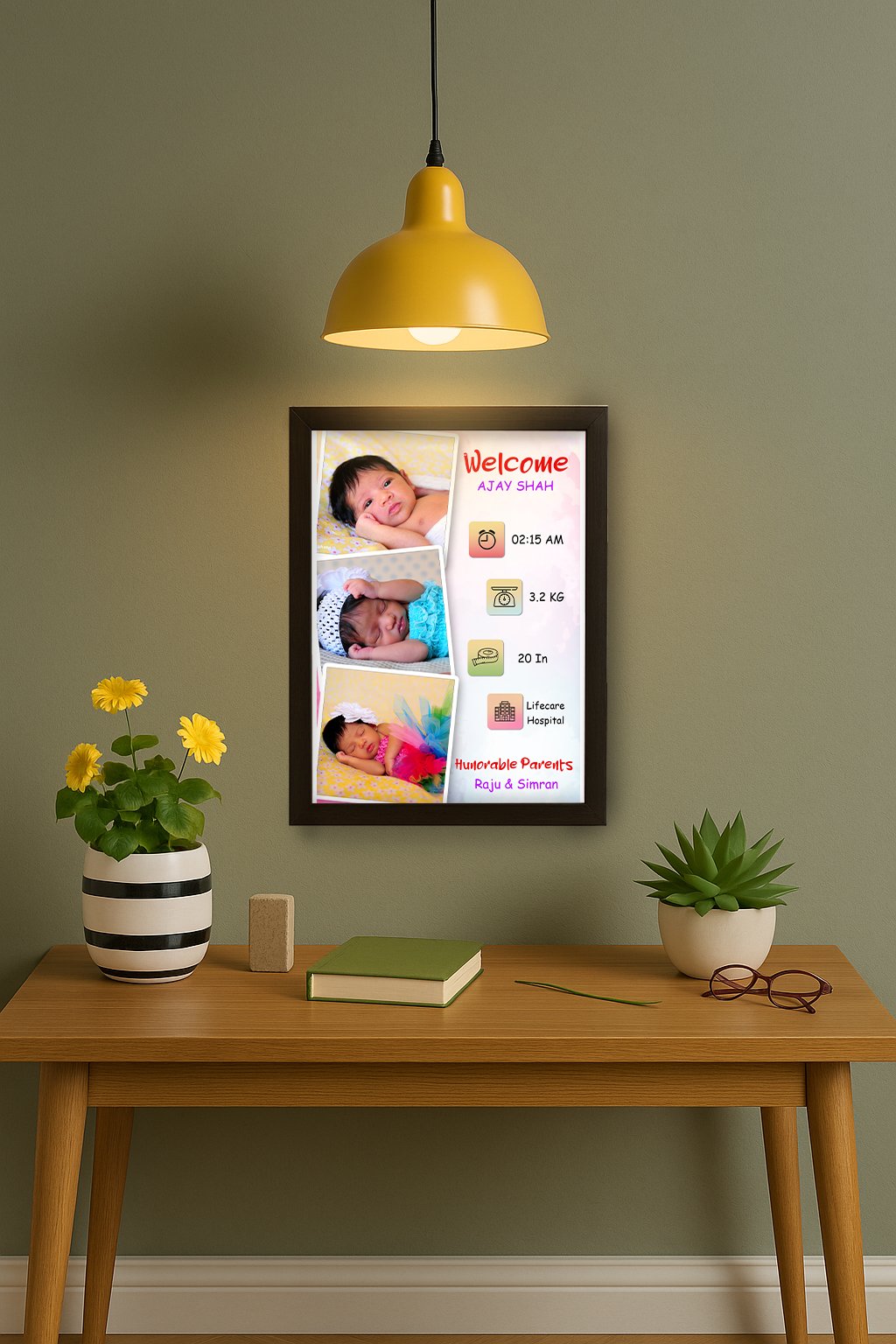 A framed Personalized Baby Birth Frame hanging on a green wall, featuring three photos of a baby, along with text detailing "Welcome," baby's name (Ajay Shah), birth time (02:15 AM), weight (3.2 KG), length (20 In), hospital (Lifecare Hospital), and parents' names (Raju & Simran), illuminated by a yellow hanging lamp.