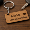 A rectangular light brown "MDF keychain" with rounded corners, engraved with "Drive Safe I need you here with me" text and a small heart icon,