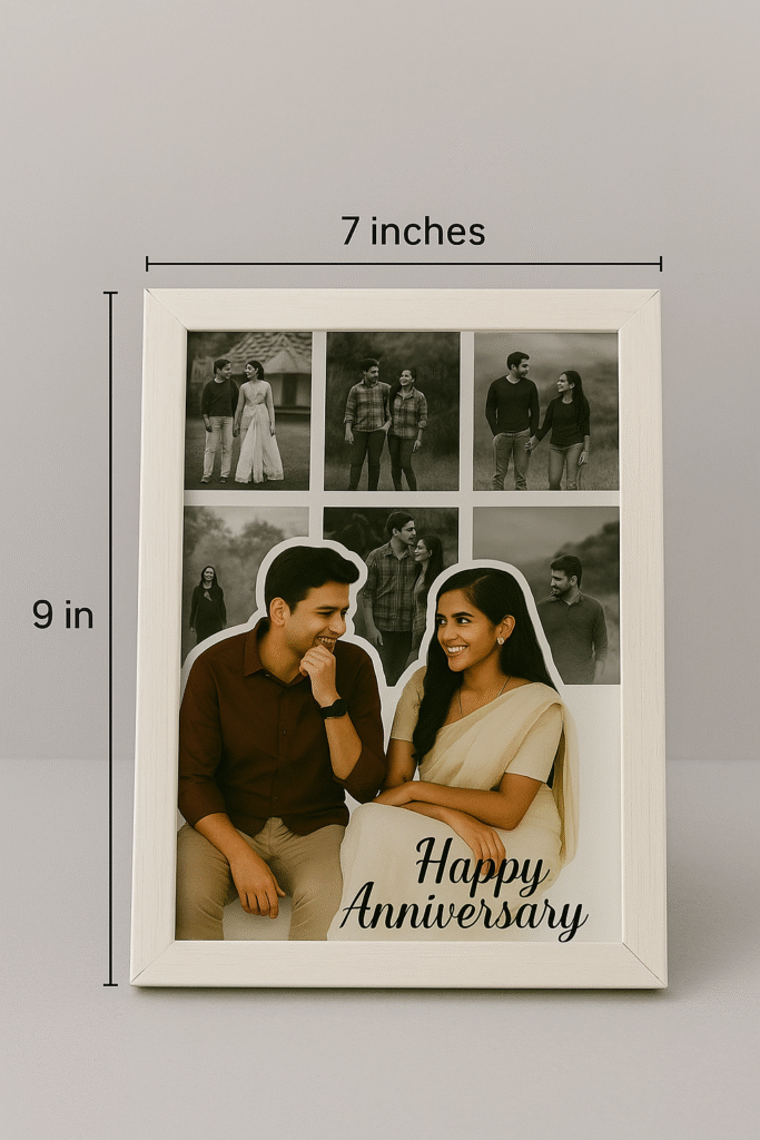 A white-framed Romantic Anniversary Photo Collage Frame featuring a main photo of a couple and smaller surrounding photos, with "Happy Anniversary" text, on a wooden table next to a vase