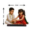 A "Rakhi Caricature for Brother and Sister" depicting a personalized standee of a young boy and girl in traditional attire, with a Rakhi thali between them, celebrating Raksha Bandhan, set against a bokeh background.