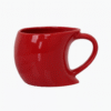Custom Red Singapore Mug with a curved base and a unique handle shape, filled with coffee, sitting on a wooden desk next to a laptop and a pencil holder.
