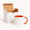 Orange and White Ceramic Coffee Mug a bright orange interior and handle, sitting on a table with an antique clock.