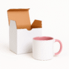 Custom Pink and white ceramic coffee mug with a pink interior and handle, sitting on a wooden table next to a vase with pink flowers, a stack of books, and scattered coffee beans.