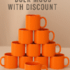Personalize Full Orange Ceramic Coffee Mug the text "YOUR LOGO HERE" printed on the side, sitting on an office desk next to a laptop.